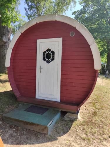 a red dog house with a door in it at TinyHouse "Comet" am See, an der Mecklenburger Seenplatte in Fürstenberg-Havel