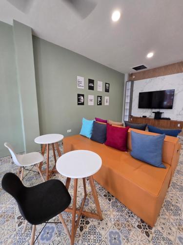 a living room with a orange couch with colorful pillows at Rebahan Stay in Surabaya