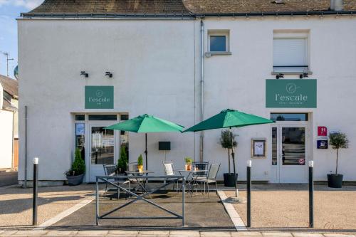 two tables with green umbrellas in front of a building at L Escale in Ports