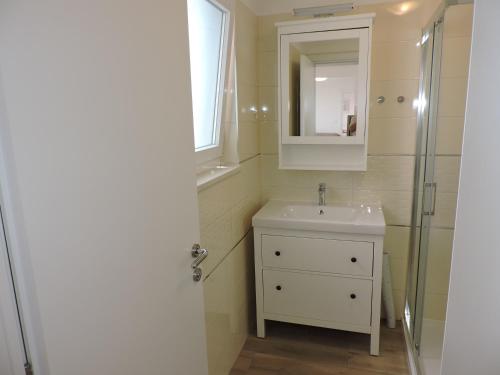 a bathroom with a sink and a mirror and a shower at Apartments Villa Elma in Mošćenička Draga