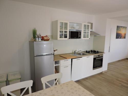a kitchen with white cabinets and a stainless steel refrigerator at Apartments Villa Elma in Mošćenička Draga