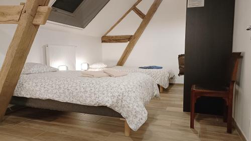 deux lits dans une chambre aux murs blancs et au parquet dans l'établissement La Grange à outeaux, à Montpont-en-Bresse