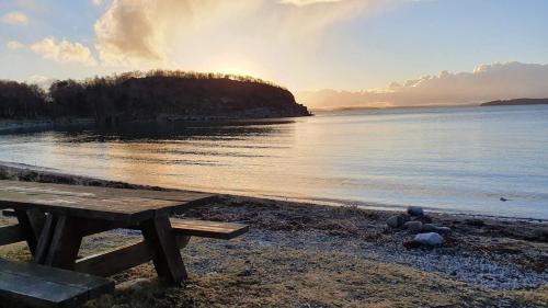a picnic table on the shore of a body of water at New apartment close to Preikestolen in Strand