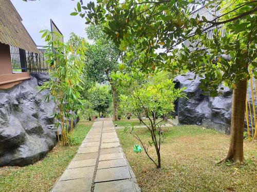 a path in a garden with trees and a building at Kap Korome Village Resort in Koroth