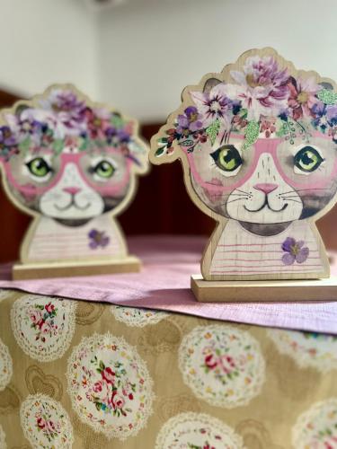 two statues of cats with flowers on their heads and cupcakes at B&B Apart Hotel Goldener Hahn - Hygge Pool & Sauna in Baiersbronn