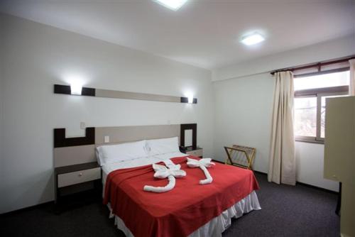 a bedroom with a bed with red sheets and white towels at Nuevo Mundo in San Rafael