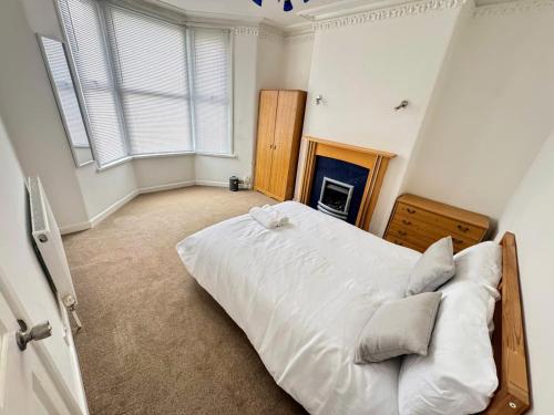 a bedroom with a large white bed and a fireplace at Bright & Cozy Private Room Near Bristol City Centre in Bristol
