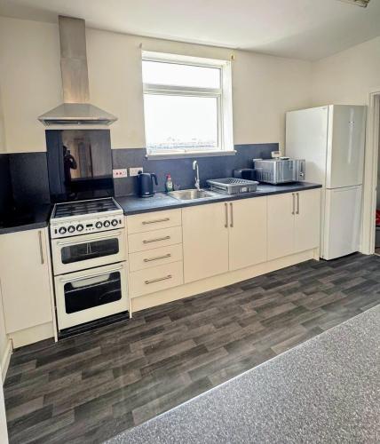 a kitchen with white cabinets and a stove and a sink at Bright & Cozy Private Room Near Bristol City Centre in Bristol