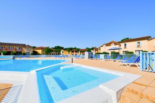 - une grande piscine avec des chaises bleues dans un complexe dans l'établissement La résidence du Lac - maeva Home - Maison 3 pièces 6 personnes - Sélection MAE-3941, à Monflanquin