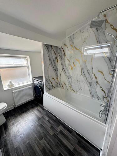 a bathroom with a tub and a marble wall at Compact Budget Room - 9 Mins to Bristol Centre in Bristol
