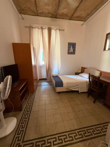a bedroom with a bed and a desk and curtains at Soggiorno Emanuela in Rome
