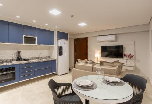 a kitchen and living room with a table and chairs at Maranatha Suítes in Campo Grande