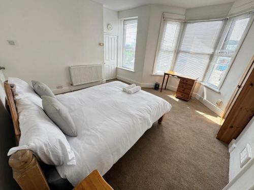 a bedroom with a bed with white sheets and pillows at Spacious Private Room - 9 Minutes from Central Bristol in Bristol