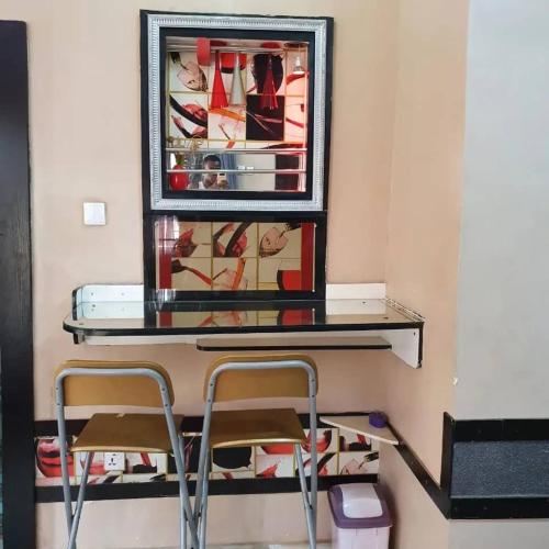 a shelf with two chairs and a mirror on a wall at Goldbond Service Apartment in Abeokuta