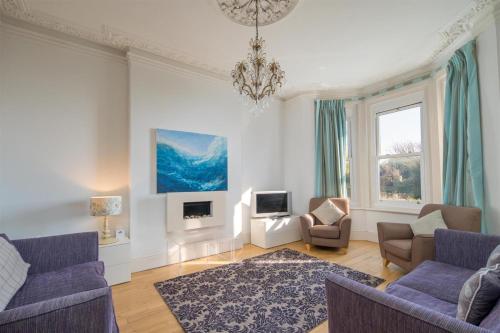a living room with blue chairs and a chandelier at Villa Lavinia in Ventnor