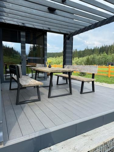 a picnic table and two benches on a deck at The Prut Lodge in Vorokhta