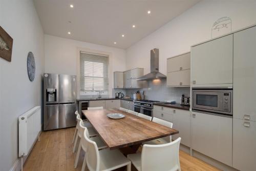 a kitchen with a wooden table and white cabinets at Villa Lavinia in Ventnor
