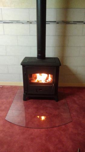 a black stove in a room with a red floor at F2 appartement de campagne in Cramans