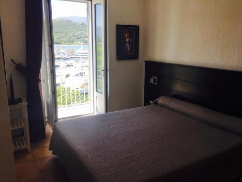 a bedroom with a bed and a large window at Hotel Restaurant L'Europe in Saint-Florent