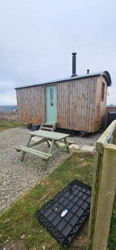 una mesa de picnic frente a un edificio de madera en Shepherds Hut, en Mawgan Porth