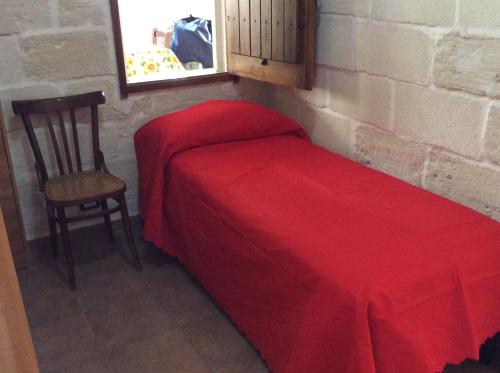 a bed with a red blanket and a chair in a room at Favignana Vacanze in Favignana