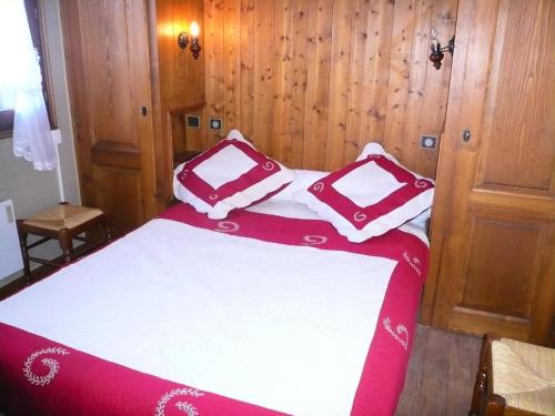 Cette chambre comprend un lit avec des oreillers rouges et blancs. dans l'établissement Résidence Les Terrasses Du Mont Blanc - 2 Pièces pour 6 Personnes 17, à Combloux