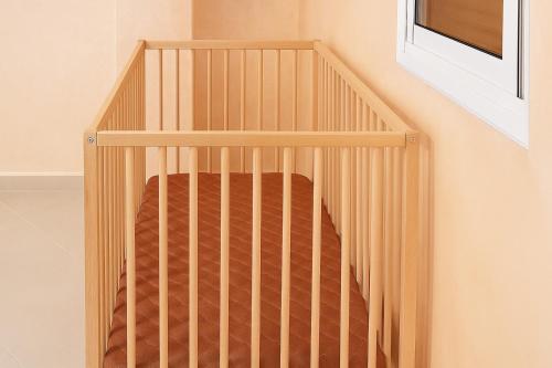 a wooden crib in a childs room at Panorama Apartment Nador Jadid Klima Parking Only Family in Nador
