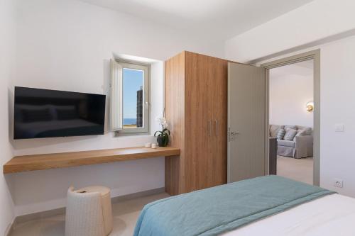 a bedroom with a flat screen tv on a wall at Platies Luxury Apartments Santorini in Éxo Goniá