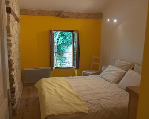 a yellow bedroom with a bed and a window at Maison de village provençale Mollans-Dru in Mollans-sur-Ouvèze