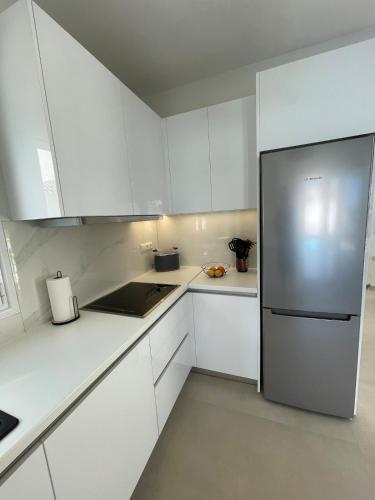 a kitchen with white cabinets and a stainless steel refrigerator at Villa Yimaré mit privatem Pool und Meerblick in Gázion