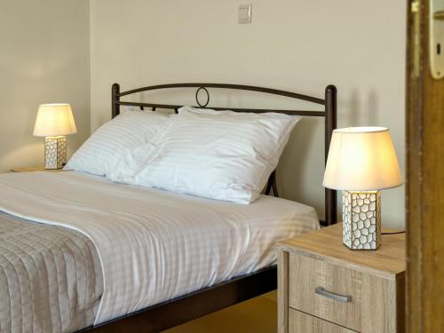 a bedroom with a bed with two lamps on a night stand at Traditional Stone House in Kranidi