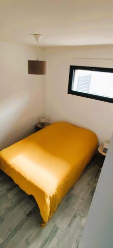 - un lit jaune dans une chambre avec fenêtre dans l'établissement Petite maison de vacances proche de la mer, à Wimereux