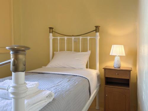 a bedroom with a white bed and a nightstand with a lamp at Traditional Stone House in Kranidi