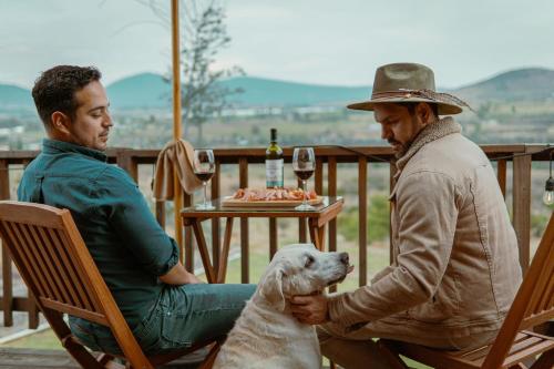 two men sitting at a table with a dog at La Cabaña Alpina de Huimilpan in Pedro Escobedo