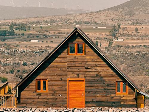 a log cabin with orange doors on a field at La Cabaña Alpina de Huimilpan in Pedro Escobedo