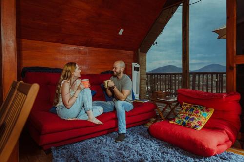 a man and a woman sitting on a red couch at La Cabaña Alpina de Huimilpan in Pedro Escobedo