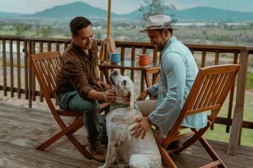 two men sitting in chairs petting a dog on a porch at La Cabaña Alpina de Huimilpan in Pedro Escobedo