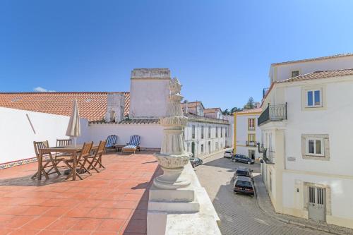 a balcony with a table and chairs and buildings at Império House in Santiago do Cacém