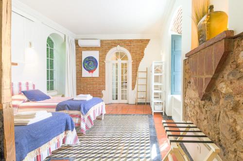 a room with two beds and a brick wall at Império House in Santiago do Cacém