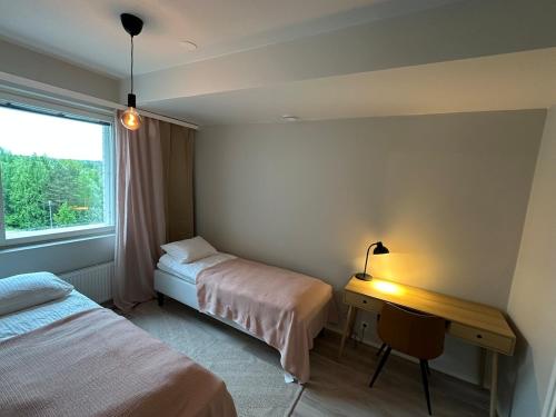 a bedroom with two beds and a desk and a window at Apartment in Kuopio's Archipelago City in Kuopio