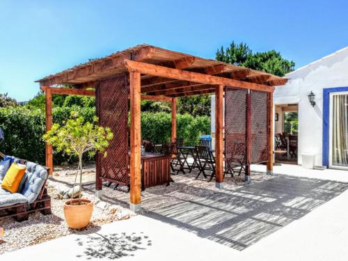 a wooden pergola with a table and a couch at Onda Vicentina Guesthouse in Aljezur
