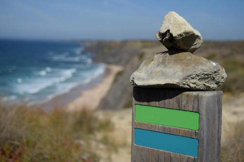 a rock on top of a wooden post with a beach at Onda Vicentina Guesthouse in Aljezur