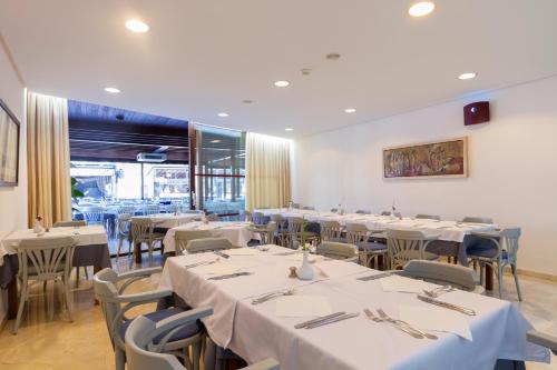 a dining room with tables and chairs with white tablecloths at Duvabitat Apartments in Port de Pollensa