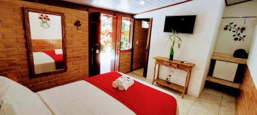 a bedroom with a bed with a red blanket and a tv at Portal Suítes Casa do Lago in Paraty