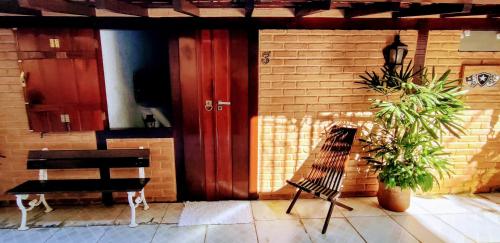 a building with red doors and a bench and a plant at Portal Suítes Casa do Lago in Paraty