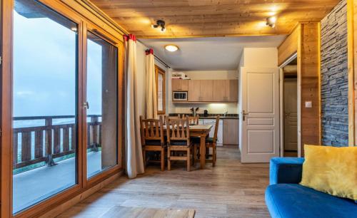 un salon avec un canapé bleu et une salle à manger avec un balcon dans l'établissement Résidence Le Balcon Des Airelles - Appartement rénové avec jolie vue sur la vallée MAE-6774, aux Orres