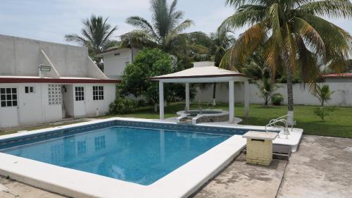 a swimming pool with a gazebo next to a house at Casa, alberca privada y jardín in Tecolutla