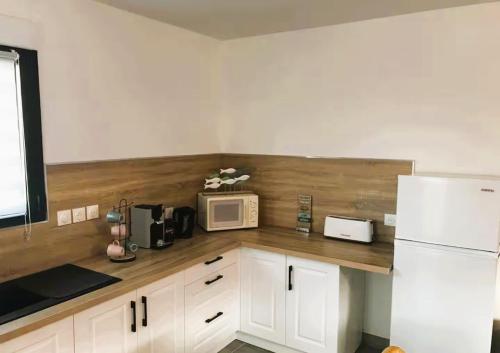 La cuisine est équipée de placards blancs et d'un four micro-ondes blanc. dans l'établissement Petite maison de vacances proche de la mer, à Wimereux