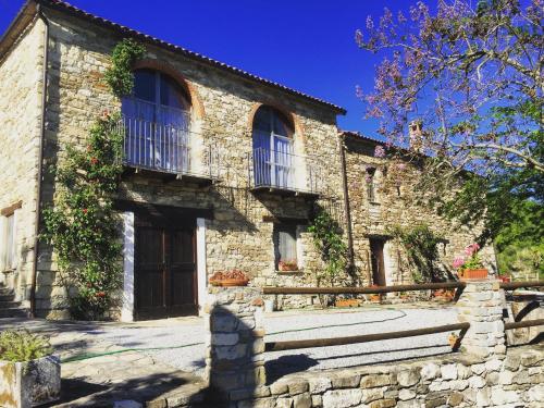 an old stone house with a porch and a balcony at Cascina Bertolotto Wine Resort in Spigno Monferrato