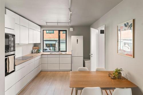 a kitchen with a wooden table and white cabinets at Heart of Tønsberg, Newly renovated, Room for 6 people! in Tønsberg